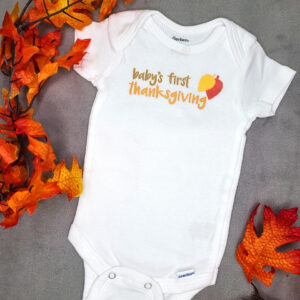 Baby's First Thanksgiving bodysuit displayed with fall leaves